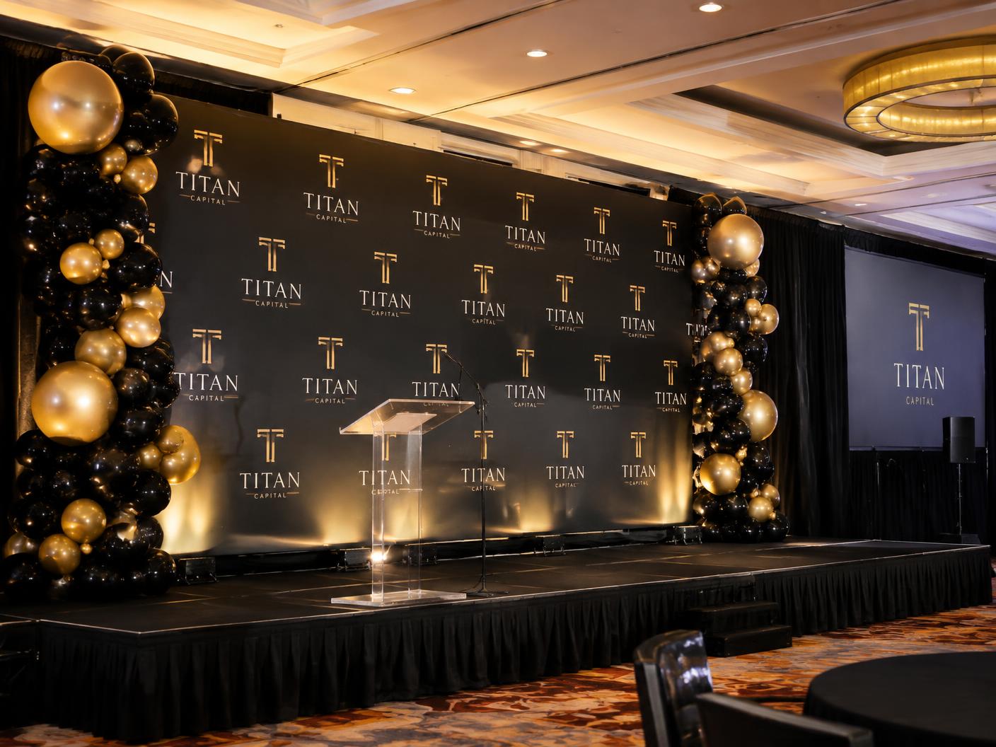 Black and gold balloon columns framing a branded corporate stage backdrop